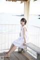 A woman in a white dress sitting on a wooden bench.