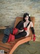 A woman in a black and red outfit sitting on a wooden bench.