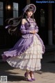 A woman in a purple and white dress is posing for a picture.