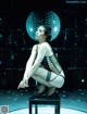 A woman sitting on a stool in front of a disco ball.