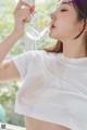 A woman drinking water from a glass with a flower in it.