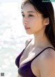 A woman in a purple bikini standing on the beach.