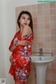 A woman in a red kimono standing in front of a sink.