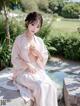 A woman in a pink kimono sitting on a stone ledge.