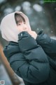 A woman wearing a black jacket and a white hat in the snow.