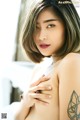 A woman with a tattoo on her arm is posing for a picture.