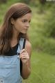 A young woman in overalls standing in a field.