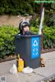 A woman sitting in a trash can next to a bunch of rabbits.