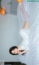 A woman laying on top of a bed in a white dress.