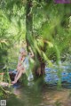 A woman sitting on a tree branch in the water.