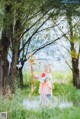 A woman in a pink dress holding a wand in a field.