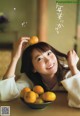 A woman sitting at a table with a bowl of oranges.