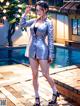 A woman in a silver suit standing next to a pool.