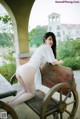 A woman in a white dress sitting on a wooden bench.