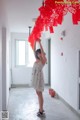 A woman in a white dress holding up a red chandelier.