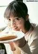 A woman holding a plate with a piece of bread on it.