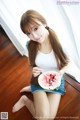 A woman sitting on the floor eating a slice of watermelon.