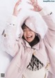 A young girl in a pink coat playing in the snow.