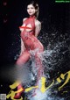 A woman in a red fishnet bodysuit is splashing in the water.