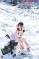 A woman sitting on a log in the snow.