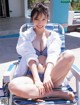 A woman in a blue and white bikini sitting on a beach chair.