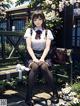 A girl sitting on a bench in a school uniform.