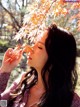 A woman holding a leaf in front of her face.