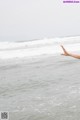 A person's hand reaching out to the ocean.