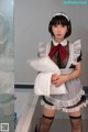 A woman in a maid outfit holding a pillow.