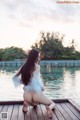 A woman sitting on a wooden dock by the water.